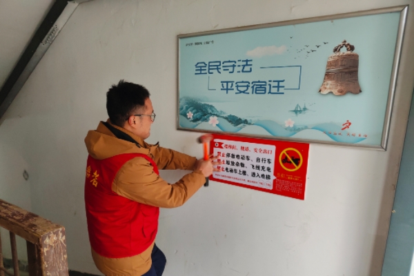 3,志愿者在居民楼道内安装电动车警示宣传牌.jpg
