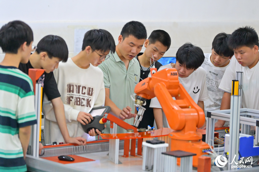 瑞金市瑞金中等专业学校工业机器人实训基地，老师在指导学生在操作智能机械臂。人民网 朱海鹏摄