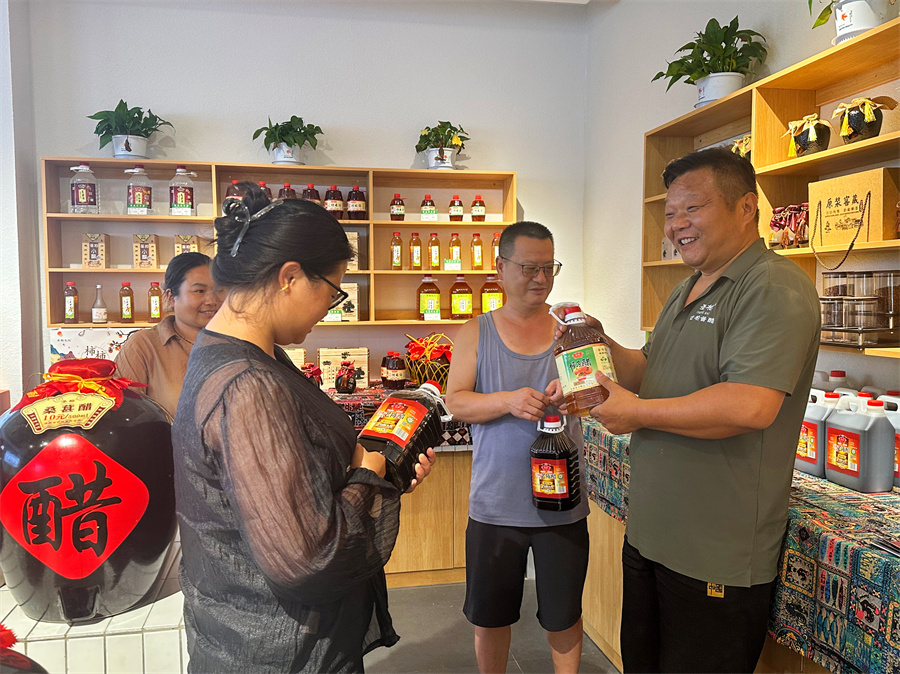 8月12日，洛南县古柏酱醋食品厂厂长王春敏（右一）给来自家门店采购柿子醋的顾客介绍产品。.jpg