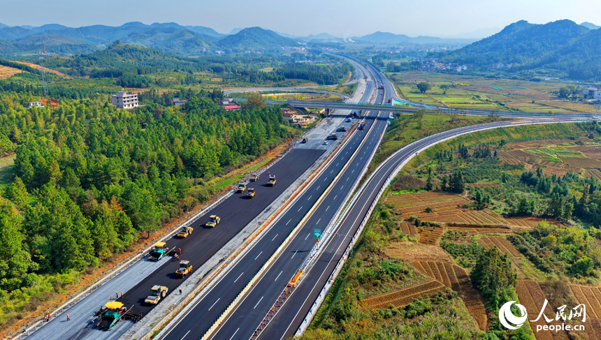 沪昆高速昌傅至金鱼石(赣湘界)段改扩建项目施工现场机械轰鸣,工人在摊铺路面沥青。人民网记者 朱海鹏摄