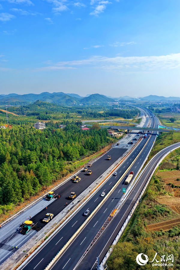 沪昆高速昌傅至金鱼石(赣湘界)段改扩建项目施工现场机械轰鸣,工人在摊铺路面沥青。人民网记者 朱海鹏摄