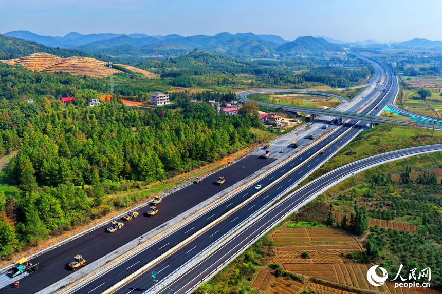 沪昆高速昌傅至金鱼石(赣湘界)段改扩建项目施工现场机械轰鸣,工人在摊铺路面沥青。人民网记者 朱海鹏摄