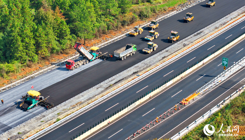 沪昆高速昌傅至金鱼石(赣湘界)段改扩建项目施工现场机械轰鸣,工人在摊铺路面沥青。人民网记者 朱海鹏摄