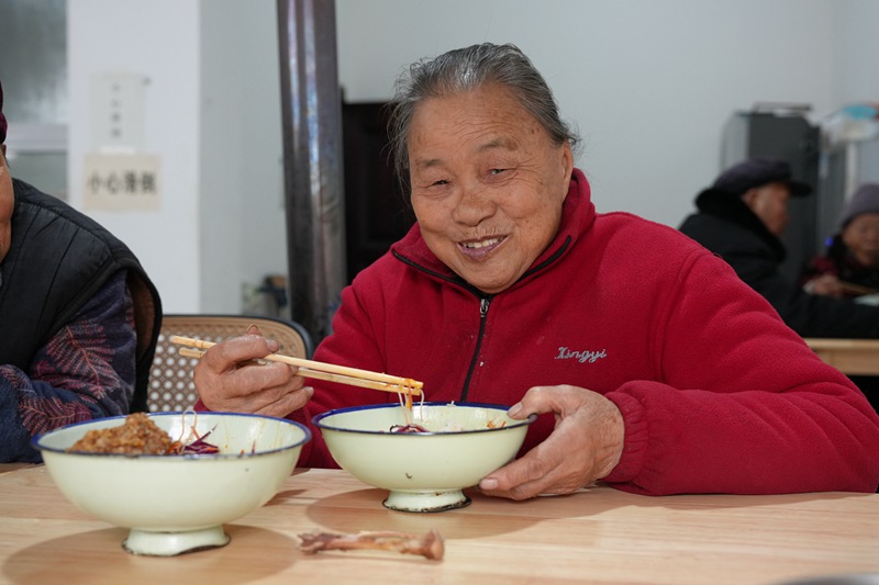 1764749087643969.jpg 老人端着热饭菜,嘴角扬起满足的笑,筷子夹起的是寻常日子的甜。高文亚 摄 (1)_副本.jpg