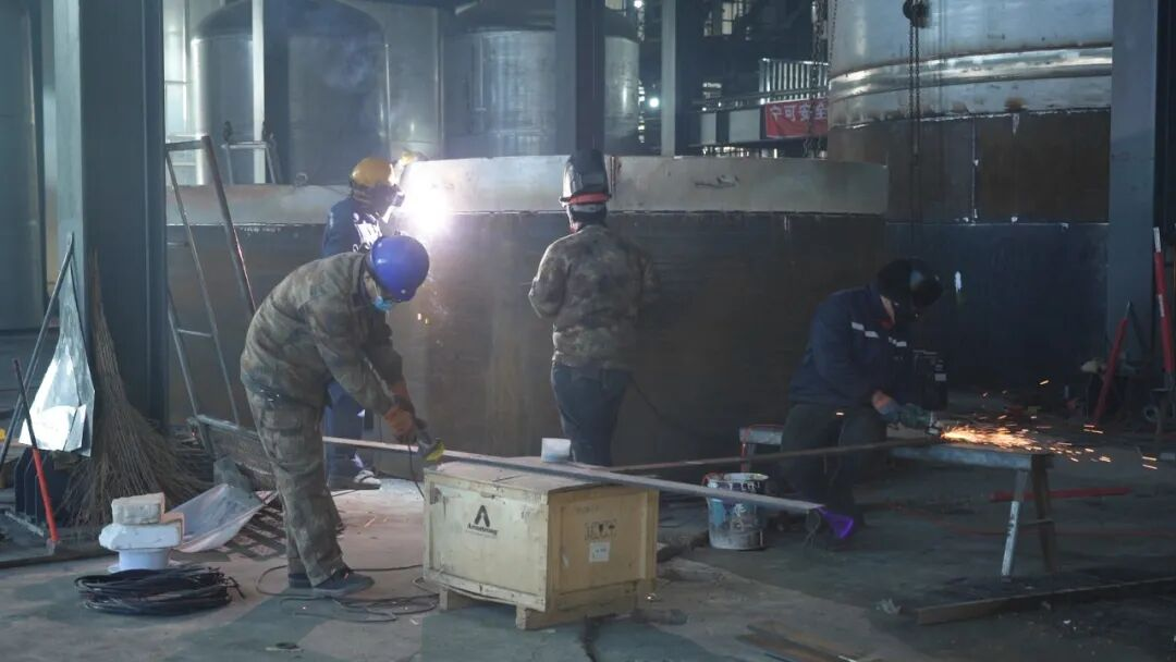 安装工人正加班加点对高12米的发酵罐进行焊接和组装  纪艾彤摄.png