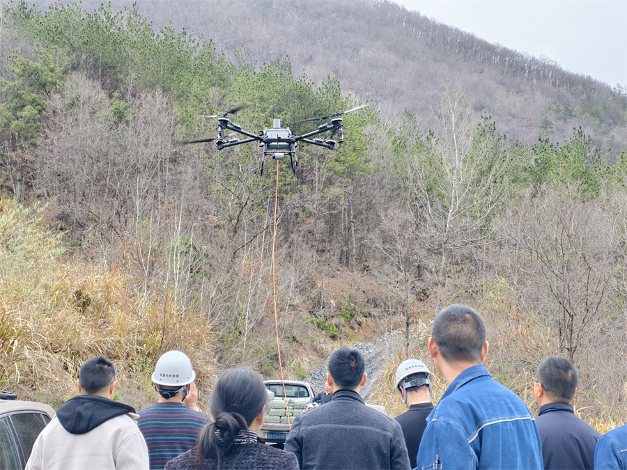 满载春耕农资的无人机平稳升空，开启深山运输作业，现场人员共同关注飞行状态.jpg