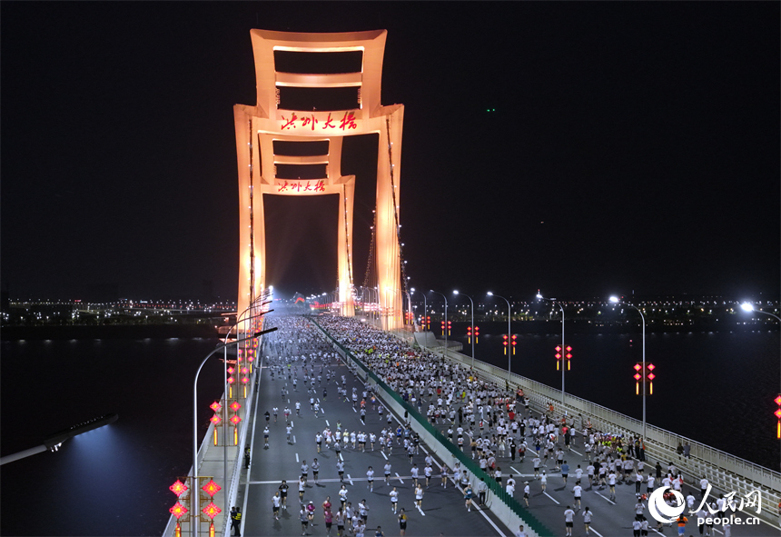 2026南昌万人夜跑活动30日晚鸣笛开跑。图为跑友奔跑在洪州大桥上。人民网记者 时雨摄