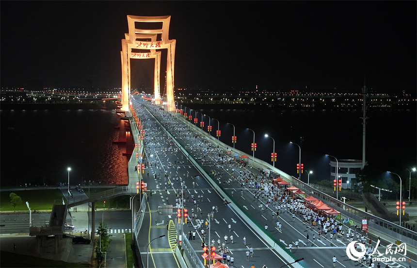 2026南昌万人夜跑活动30日晚鸣笛开跑。图为跑友奔跑在洪州大桥上。人民网记者 时雨摄