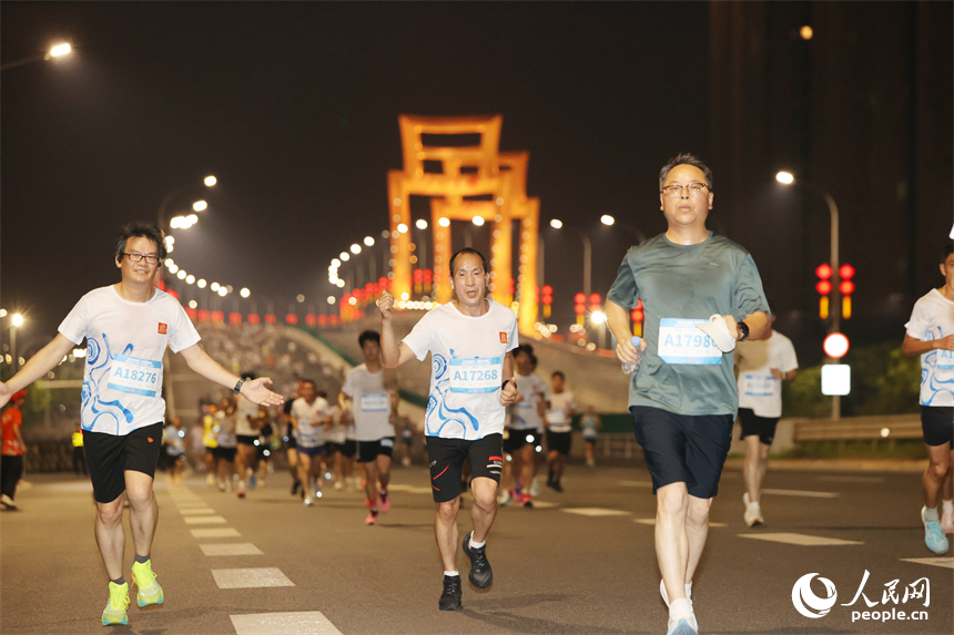 2026南昌万人夜跑活动30日晚鸣笛开跑。图为跑友奔跑在洪州大桥上。人民网记者 时雨摄