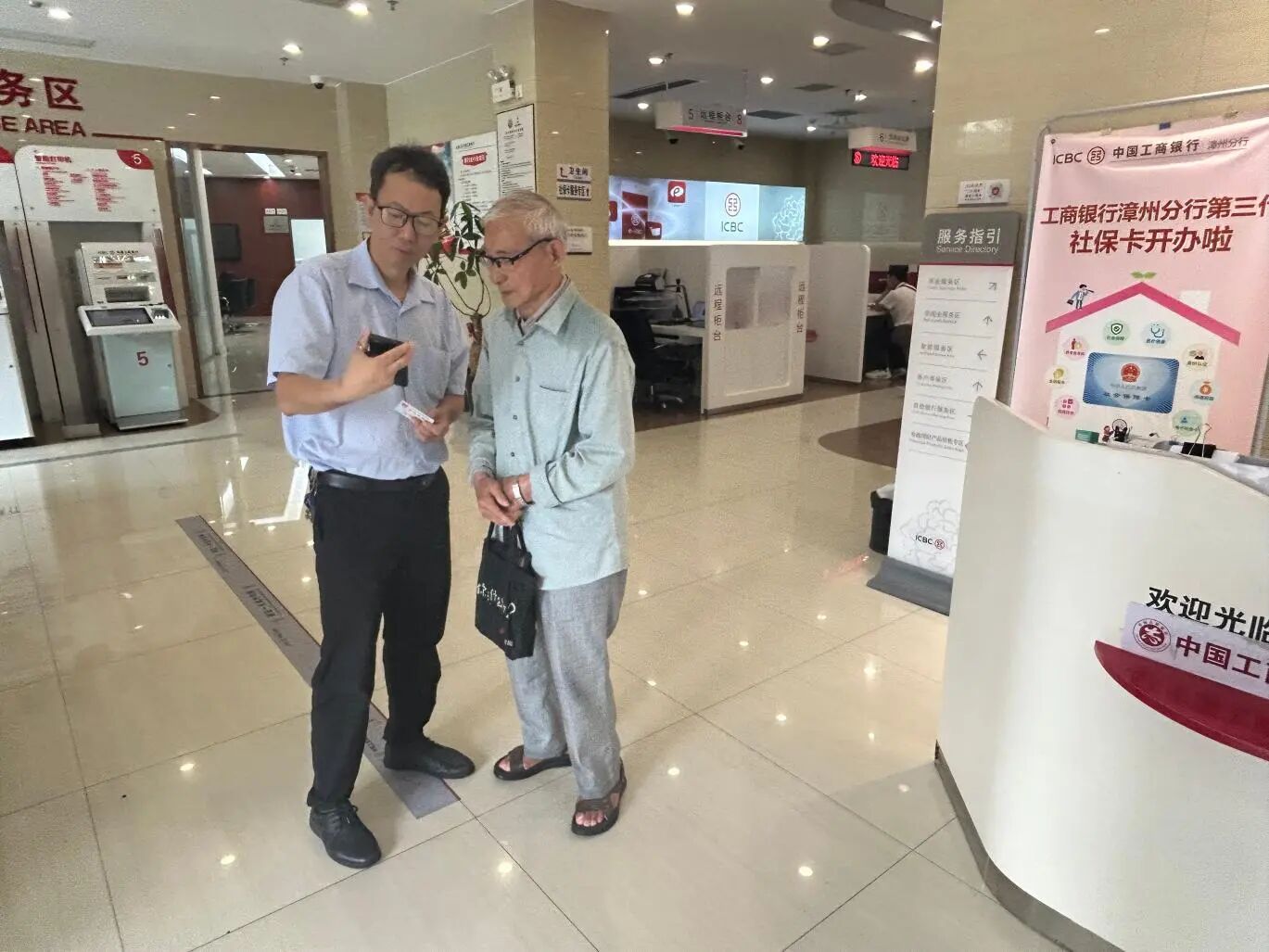 工作人员手把手协助老人完成人脸识别操作.jpg