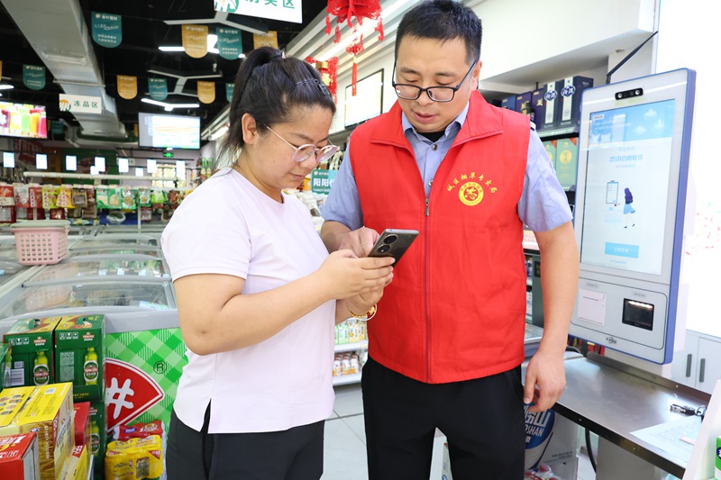 1783932654740682.jpg 图为市场监管员为辖区商户讲解烟草专卖法律法规.jpg