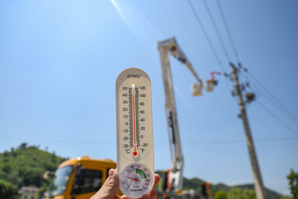 7月14日,在重庆市沙坪坝区中梁镇,国网重庆市区供电公司使用带电作业机器人为10千伏配电线路抢装接地环,温度计显示气温已超40摄氏度。