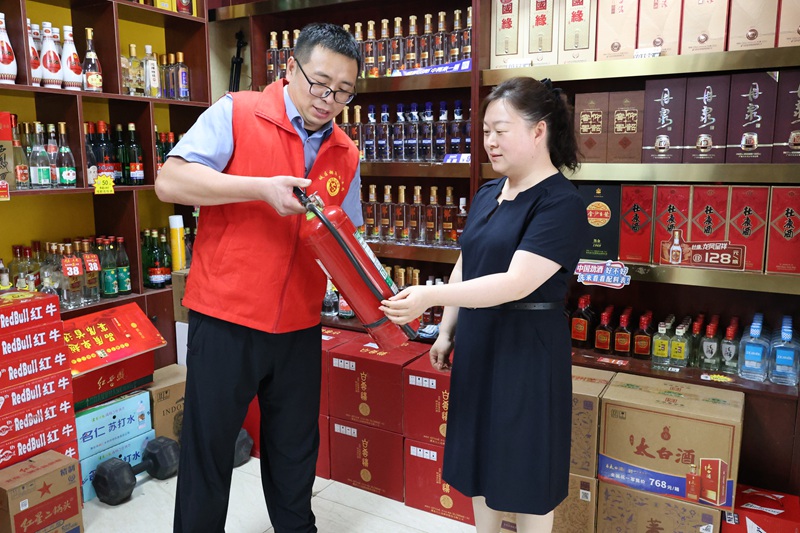 图为志愿者向商户宣传消防器材的使用方法_副本.jpg
