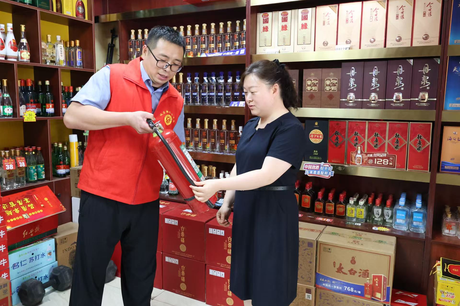 1787555676608144.jpg 图为志愿者向商户演示灭火器使用方法.jpg